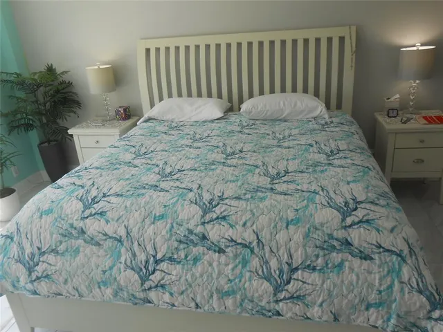 a bed sitting in a bedroom next to a lamp with potted plant