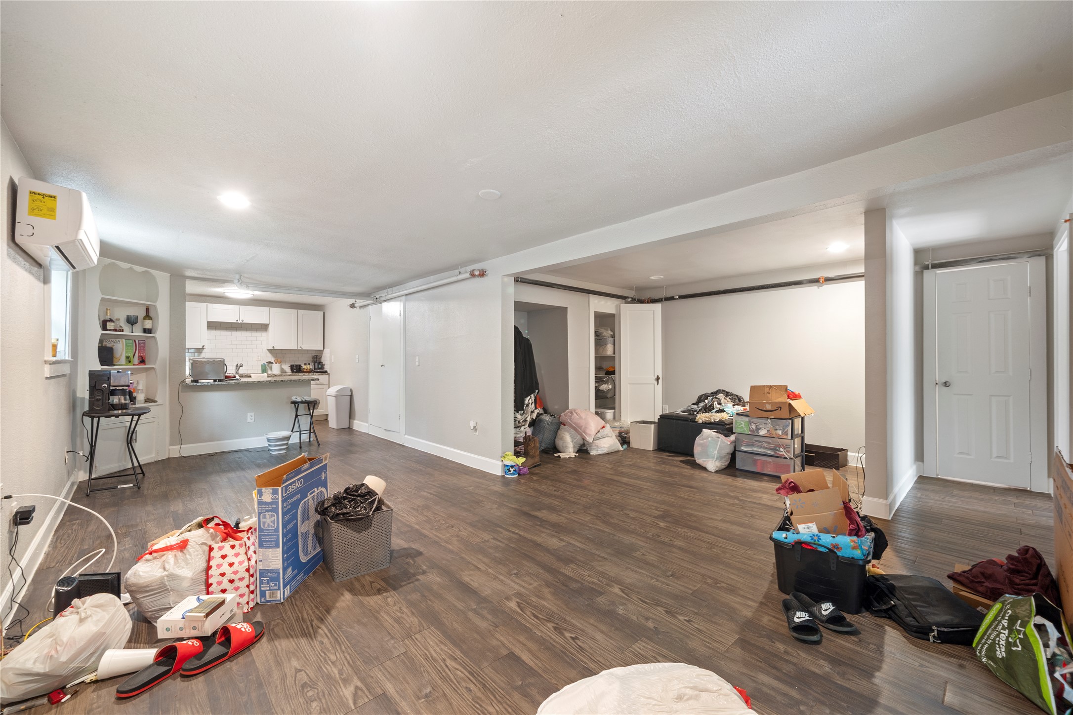 201 West 31st Street, Unit E Austin, TX 78705 - Photo 7 of 16 A versatile open-concept space featuring wood flooring and a compact kitchen area.