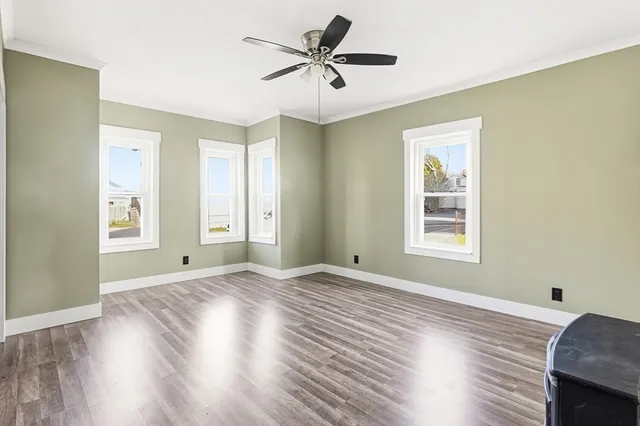 a view of empty room with wooden floor and fan
