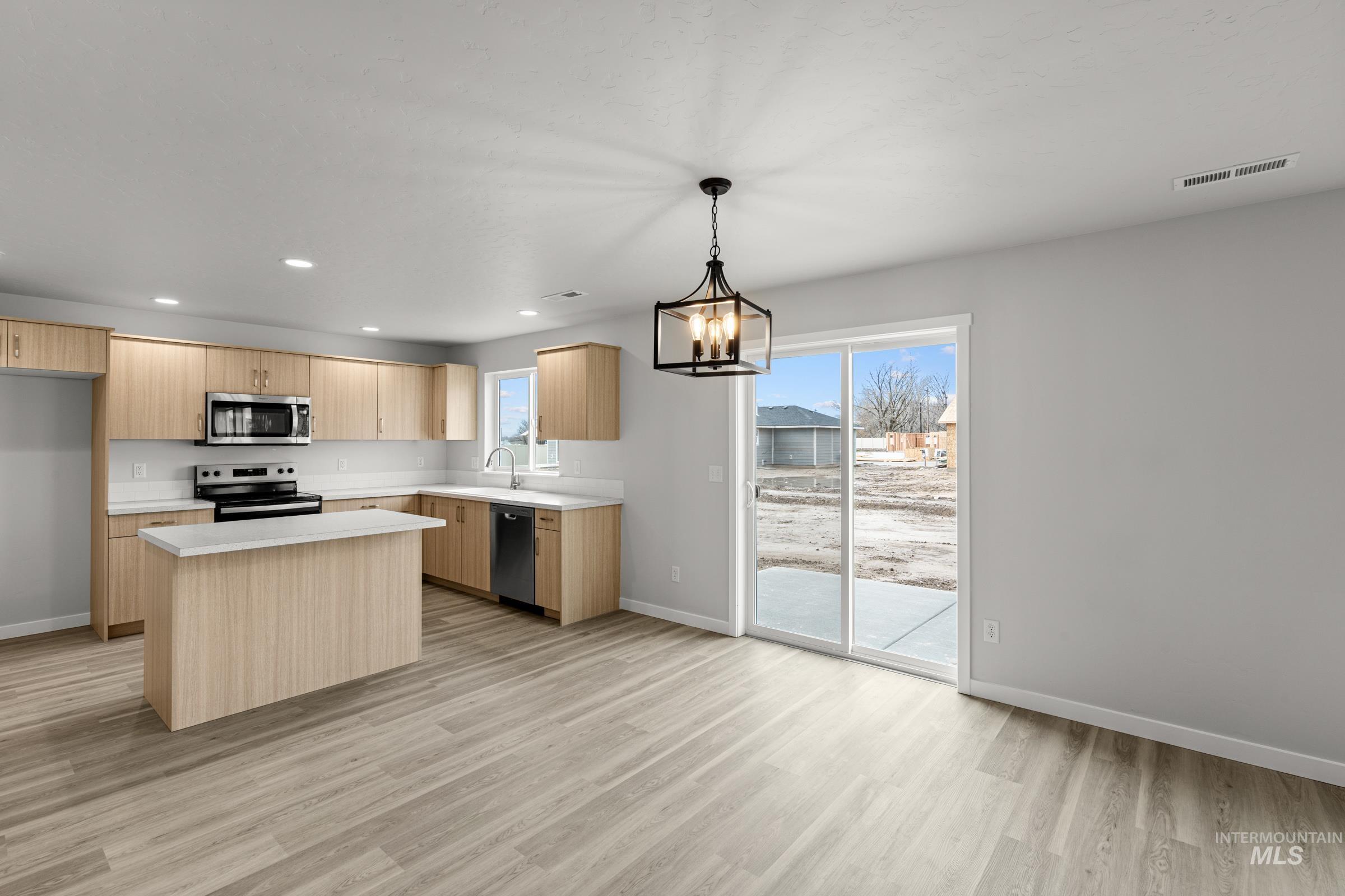14056 Shiny Spruce Street Caldwell, ID 83607 - Photo 3 of 25 Kitchen featuring wood-finish cabinetry, white countertops, stainless steel appliances, and a central island