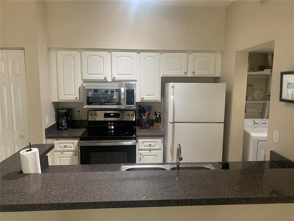 10764 70th Avenue, Unit 2301 Seminole, FL 33772 - Photo 5 of 19 a kitchen with a stove a refrigerator and a microwave