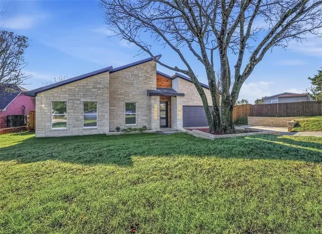 a large tree in front of a house next to a yard