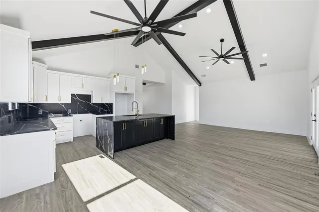 a kitchen with stainless steel appliances granite countertop a sink a stove and white cabinets