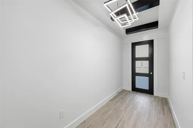 a view of an empty room with wooden floor and window