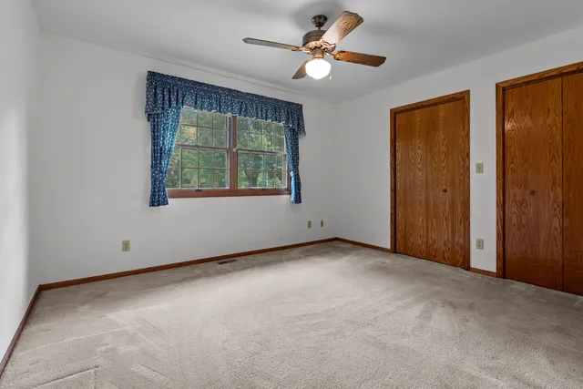 an empty room with windows and a ceiling fan