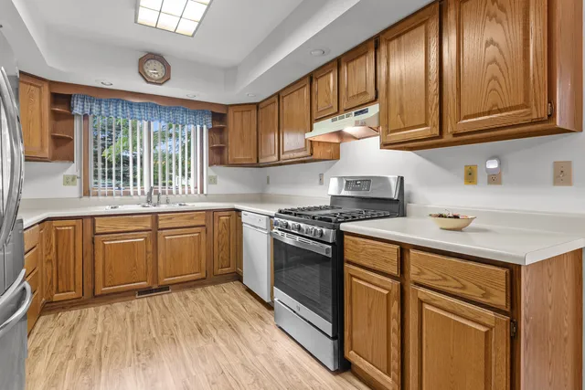 a kitchen with stainless steel appliances granite countertop a stove a sink dishwasher and cabinets with wooden floor