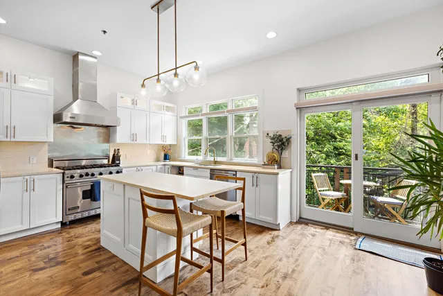 a kitchen with stainless steel appliances a stove a sink a center island and wooden floors