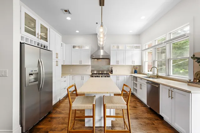 a kitchen with stainless steel appliances granite countertop a stove top oven a refrigerator a sink and a dining table with wooden floor