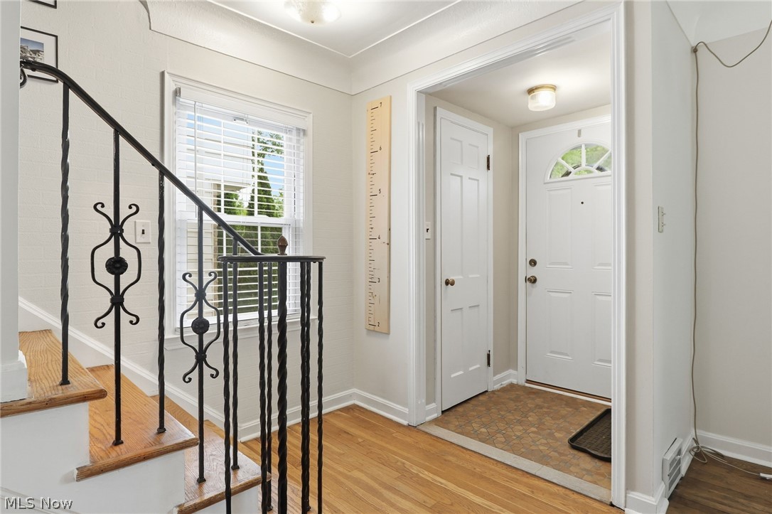 3713 Winchell Road Shaker Heights, OH 44122 - Photo 2 of 38 Entryway featuring a white paneled door with an arched transom, wood-finish flooring, a staircase with decorative wrought iron railing, and a window with blinds