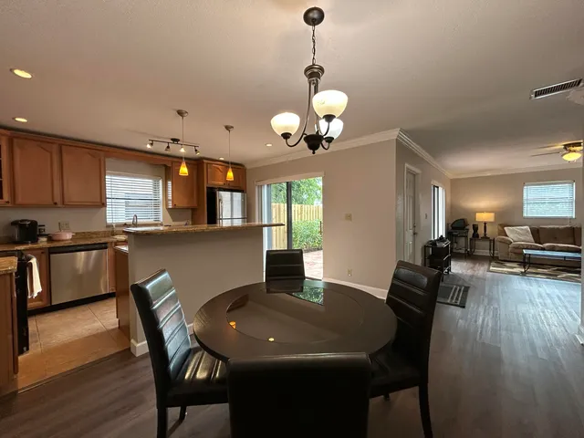 a kitchen with kitchen island a dining table chairs stainless steel appliances and cabinets