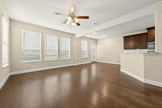 a view of a livingroom with wooden floor a ceiling fan and windows