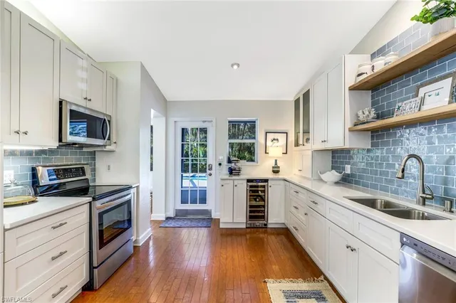 a kitchen with a sink wooden floor and stainless steel appliances