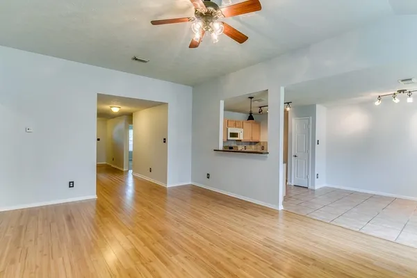a view of an empty room with window and wooden floor