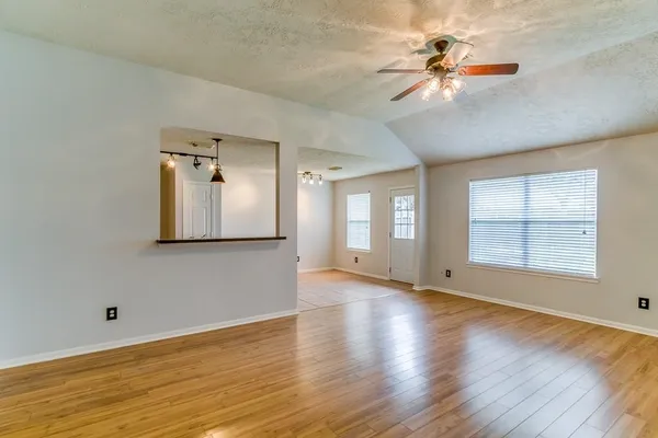 a view of an empty room with a window and wooden floor