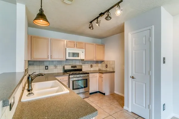 a kitchen with stainless steel appliances granite countertop a sink a stove and a refrigerator