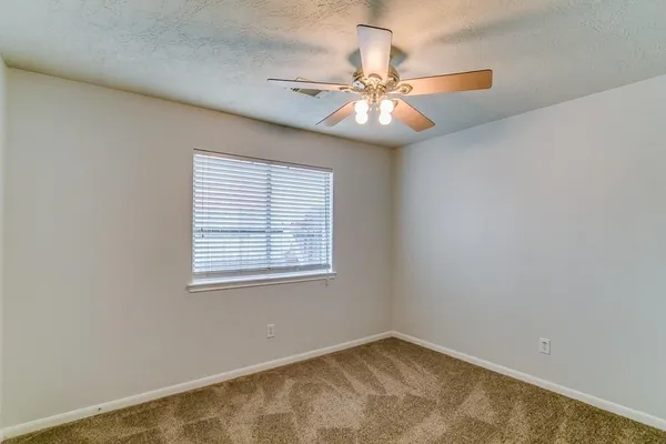 an empty room with a window and a fan