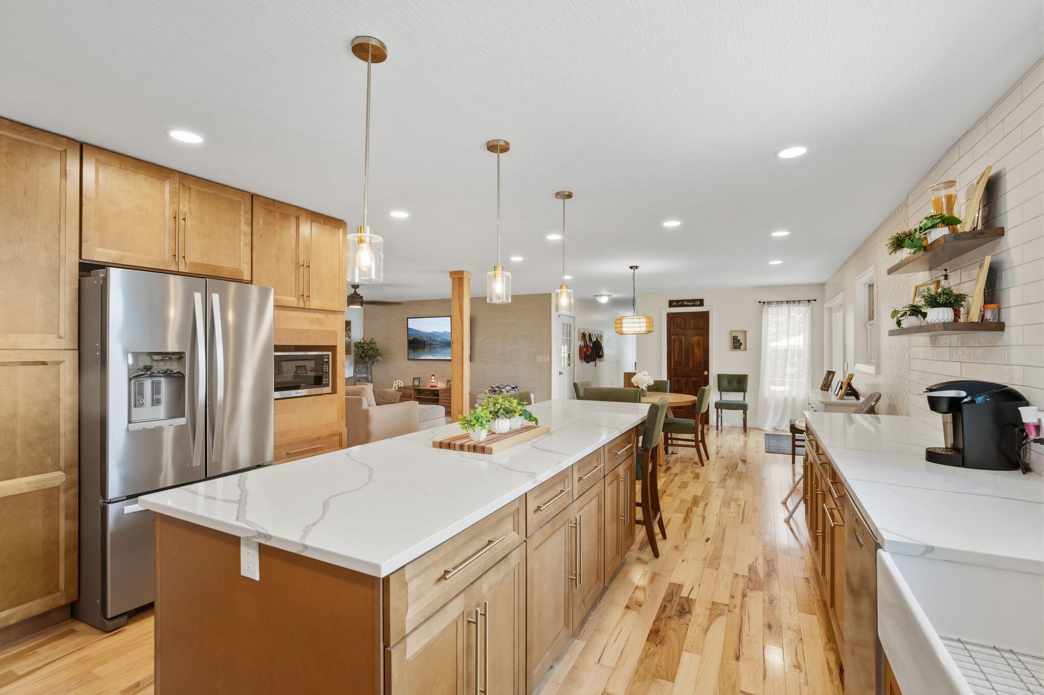 10446 Rich Hollow Road Southwest Lancaster, OH 43130 - Photo 28 of 83 Kitchen featuring a large central island with a light-toned countertop, pendant lighting, hardwood flooring, natural wood-finish cabinetry, and a subway tile backsplash