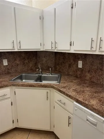 a kitchen with granite countertop white cabinets and a sink
