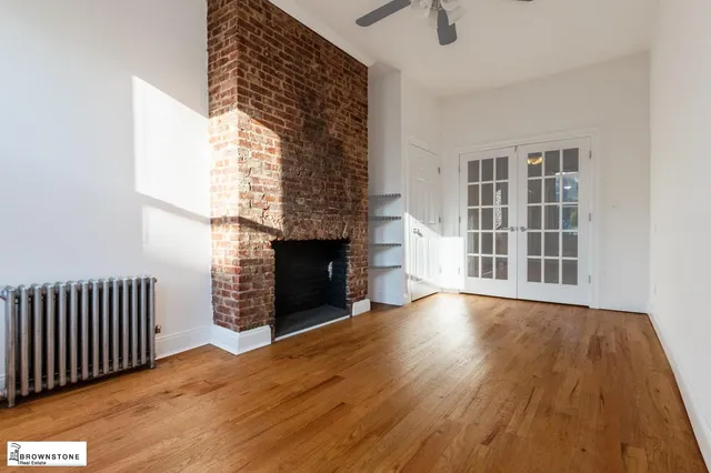 an empty room with wooden floor fireplace and windows