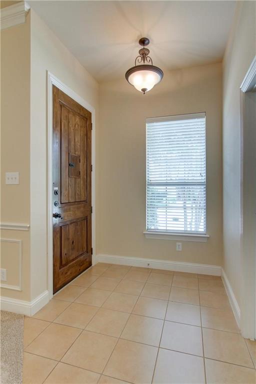 4679 Edith Street Plano, TX 75024 - Photo 6 of 34 Foyer featuring a wood-panel entry door, square tile flooring, and a pendant light fixture