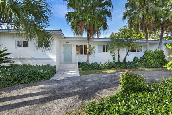 a front view of a house with a yard and palm trees