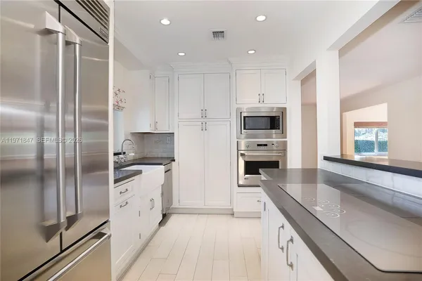 a kitchen with stainless steel appliances granite countertop a refrigerator and a stove top oven