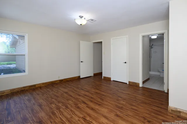 a view of an empty room with wooden floor and a window