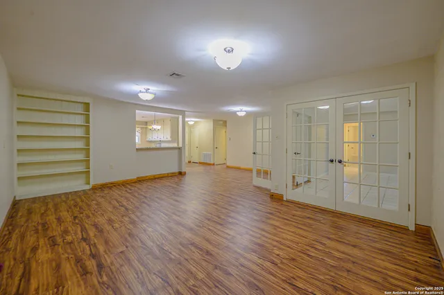 a view of empty room with wooden floor and fan
