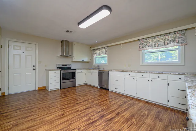 a view of a kitchen with wooden floor and electronic appliances