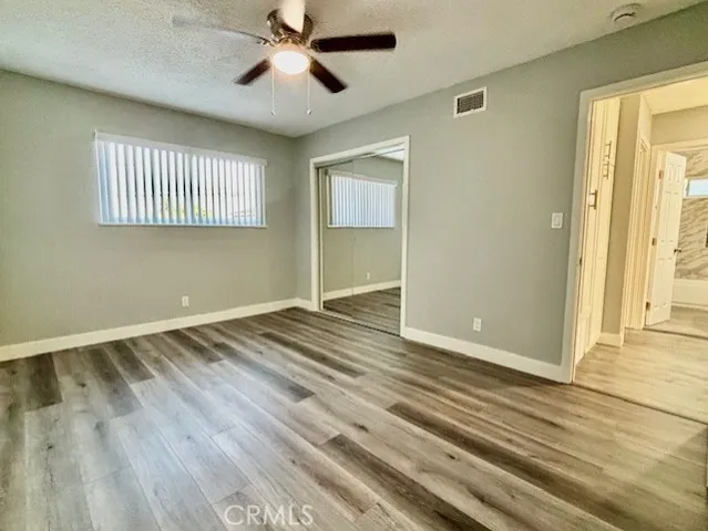 a view of empty room with wooden floor and fan