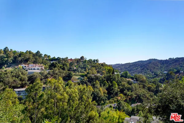 a view of a house with a street lush green forest