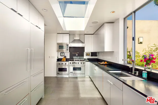 a large kitchen with stainless steel appliances kitchen island granite countertop a refrigerator and a sink