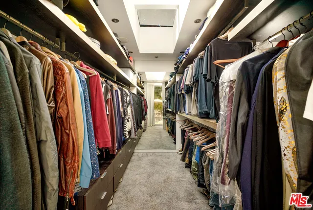 a view of walk in closet with clothes and shoes