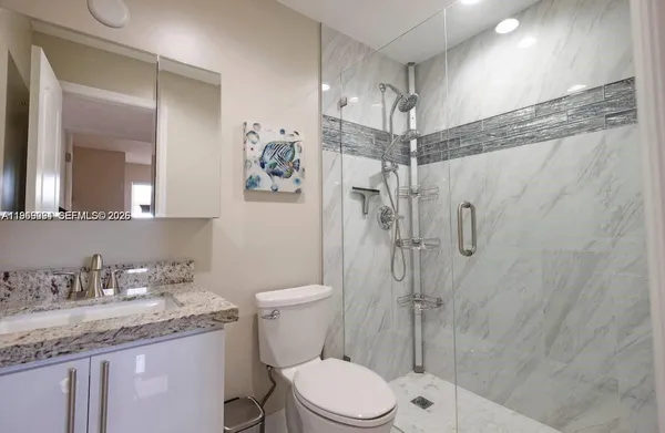 a bathroom with a granite countertop sink toilet and shower