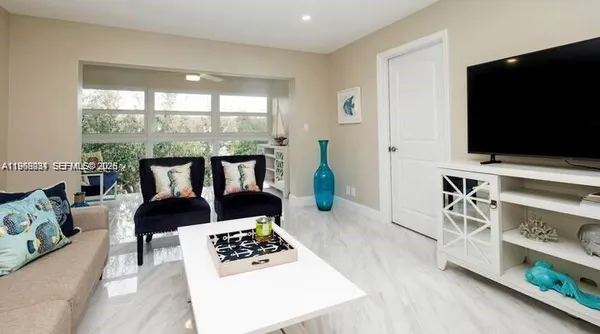 a living room with furniture a flat screen tv and a floor to ceiling window