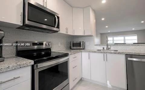 a kitchen with granite countertop white cabinets and black appliances