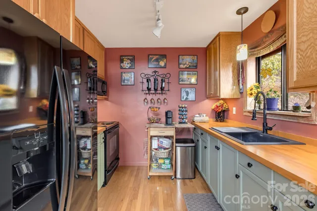 a kitchen with stainless steel appliances granite countertop a refrigerator a sink dishwasher a stove and white countertops with wooden floor