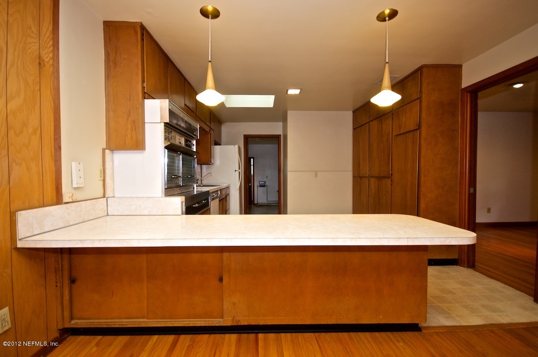 4149 Rogero Road Jacksonville, FL 32277 - Photo 13 of 27 a room with kitchen island a counter top space wooden floor and a refrigerator