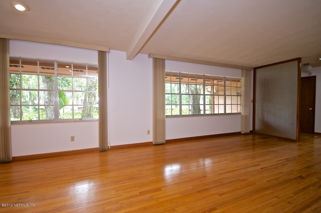 4149 Rogero Road Jacksonville, FL 32277 - Photo 8 of 27 an empty room with wooden floor and windows
