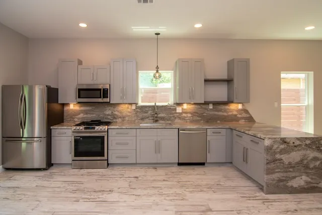 a kitchen with stainless steel appliances granite countertop a sink a stove a refrigerator and a microwave