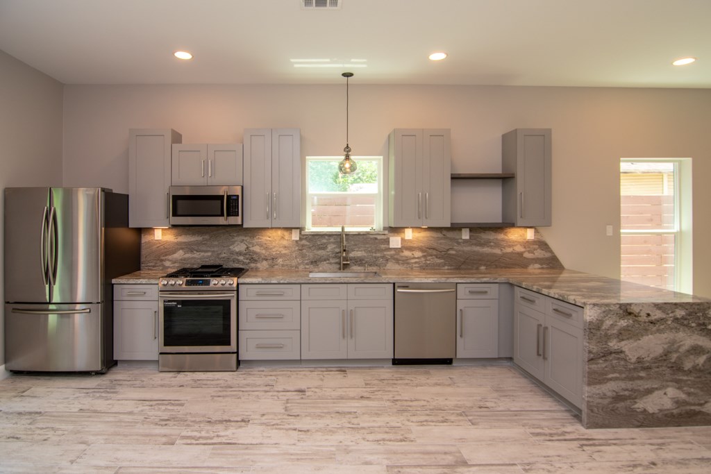 317 West 35th Street Houston, TX 77018 - Photo 10 of 22 a kitchen with stainless steel appliances granite countertop a sink a stove a refrigerator and a microwave