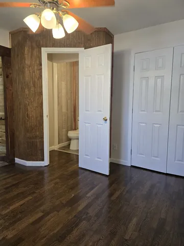 a view of an empty room with wooden floor and a mirror