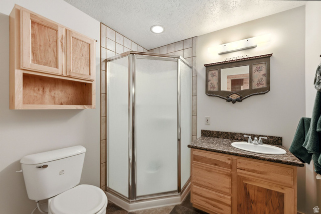 2096 South Aspen Ridge Coalville, UT 84017 - Photo 28 of 44 Corner shower with tiled surround, wood-finish vanity with countertop, and wood-finish wall cabinetry