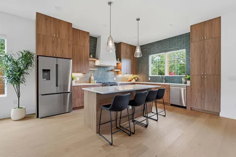 a kitchen with stainless steel appliances granite countertop a refrigerator a sink a stove a dining table and chairs