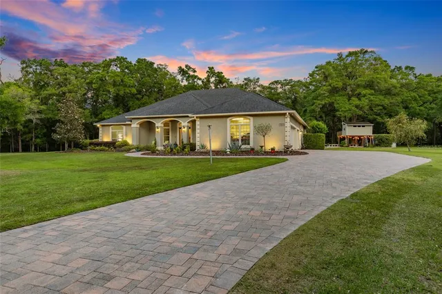 a front view of a house with a yard and trees