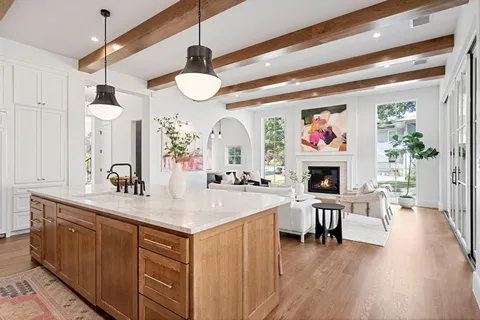 a very nice looking kitchen with a large window a fireplace and wooden floors