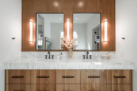 a bathroom with double sink and two mirror