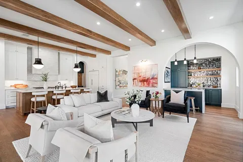 a living room with furniture kitchen view and a chandelier