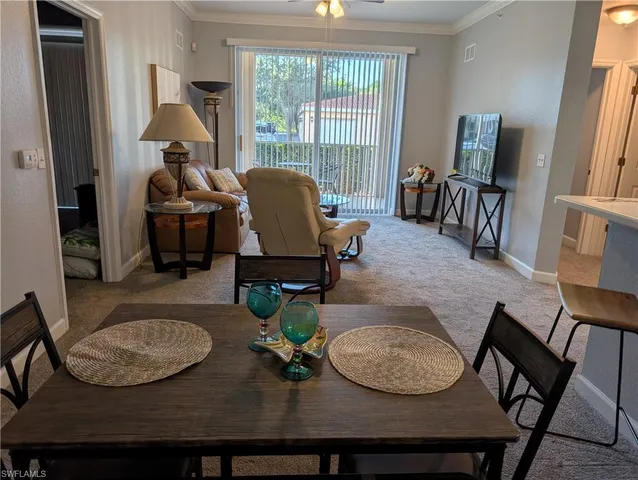 a dining room with furniture a rug a potted plant and a painting
