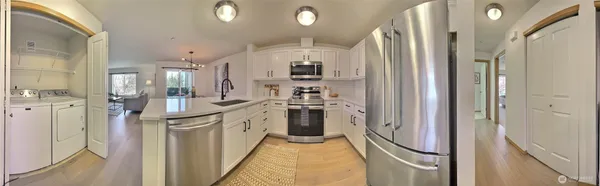 a kitchen with stainless steel appliances kitchen island granite countertop a dining table chairs and a refrigerator